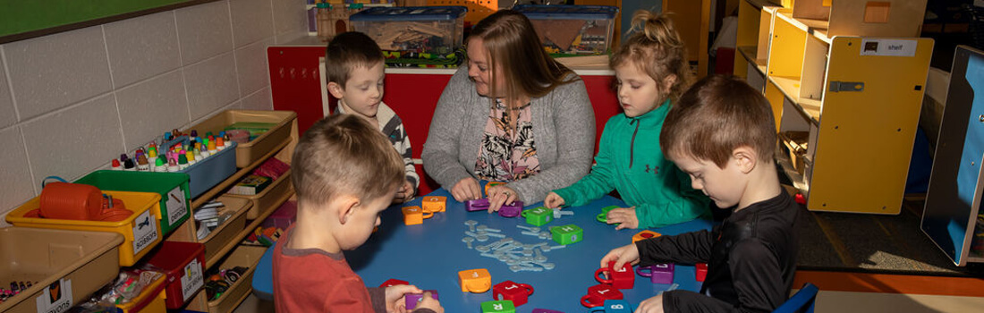Teacher sitting around table with young students